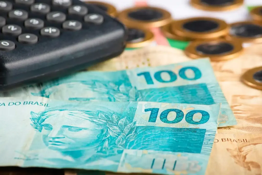 Por que o empréstimo consignado é uma escolha inteligente para servidores públicos? 4 conceito de financas notas de cem reais com calculadora e moedas dinheiro brasileiro